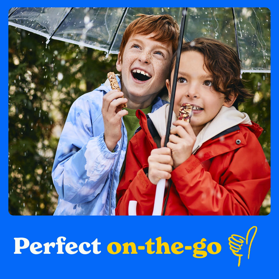 Perfect on the go: two children holding an umbrella eating MadeGood Chocolate Drizzled bars