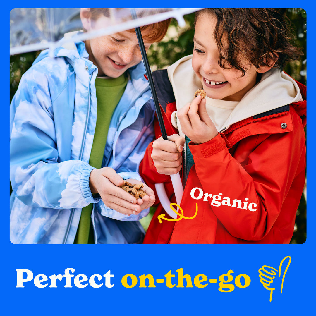 Perfect on the go: two children holding an umbrella eating MadeGood Chocolate Drizzled bars