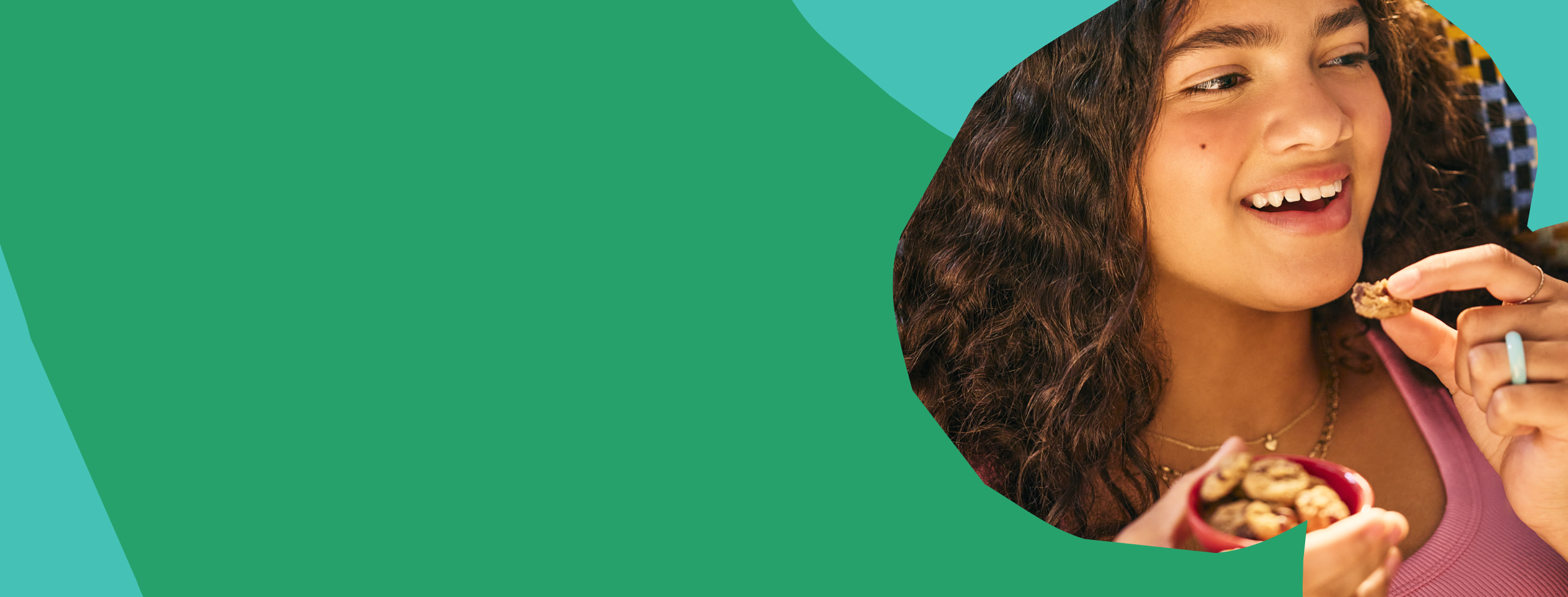 Girl eating MadeGood crunchy cookies on an abstract green and teal background. Girl eating MadeGood crunchy cookies on an abstract green and teal background.