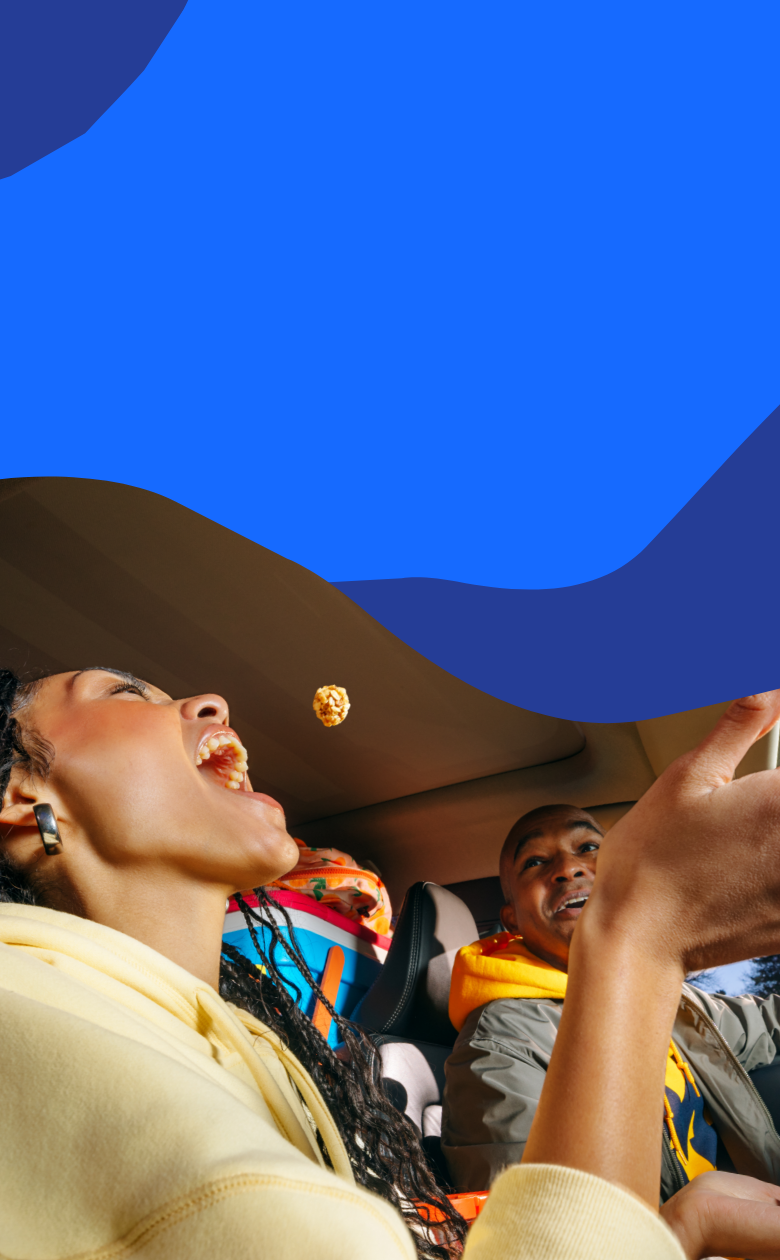 Woman eating popcorn in a car with a blue abstract background.