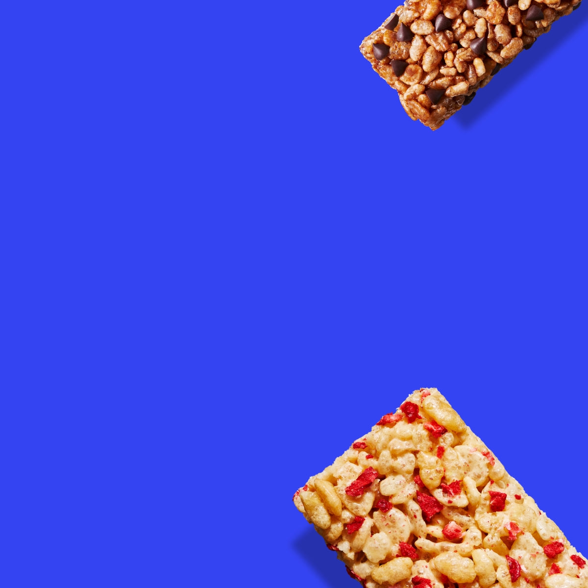 Two different rice crispy squares are placed opposite on a vibrant blue background. One has chocolate chips, and the other has red berry pieces