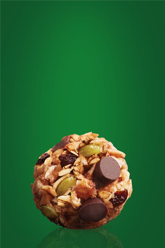 Une bouchée de mélange de randonnée MadeGood avec des pépites de chocolat, des graines de citrouille, des raisins secs, des canneberges séchées et du beurre de graines de tournesol.