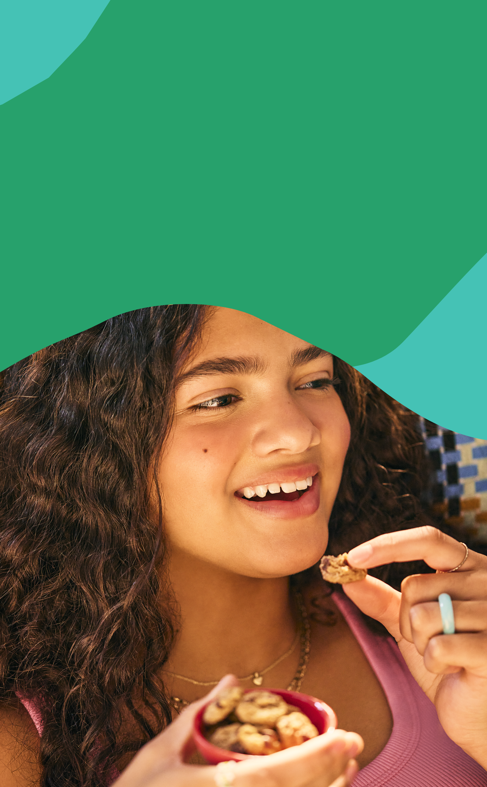 Girl eating MadeGood crunchy cookies on an abstract green and teal background.